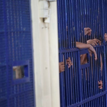 Detainees show their hands through prison bars in a Thailand jail