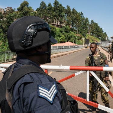 A Rwandan National Police officer watches M23 fighters.