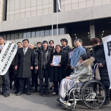 Plaintiffs holding flags declaring the verdict in front of the Tokyo district court main gate, January 26, 2026. 
