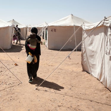 A Sudanese woman displaced from El-Fasher carries her child as she walks between tents at El-Afadh camp in Al Dabbah, in Sudan's Northern State, November 16, 2025. 