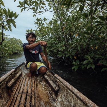 Hasael on his fishing boat moving through a mangrove forest in Siargao, Philippines, 2025.