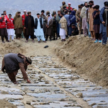 A man places stones on graves during a mass funeral for victims of the Pakistani  airstrike on the Omid drug rehabilitation center in Kabul, Afghanistan