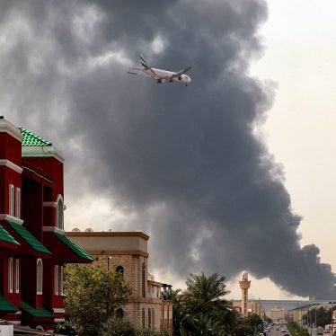 An Emirates aircraft prepares for landing as a smoke plume rises from an ongoing fire near Dubai International Airport, UAE, on March 16, 2026. 