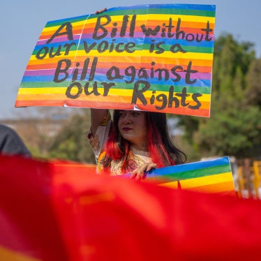 An activist holds a placard at a protest that reads "A bill without our voice is a bill against our rights"