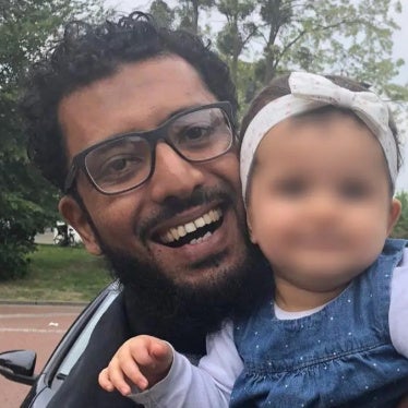 A picture of Omar smiling holding his daughter Amal