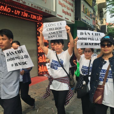  Protesters, including Can Thi Theu and Trinh Ba Tu, display placards as they march towards a courthouse during the trial of the prominent lawyer Nguyen Van Dai and five other activists in Hanoi, Vietnam, on April 5, 2018.