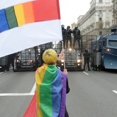 An activist waves a rainbow flag in front of a line of police