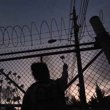 A woman places a flower on a fence outside Krome Detention Center