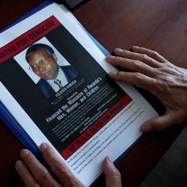The head of the Gendarmerie’s Central Office for Combating Crimes Against Humanity, Genocides and War Crimes (OCLCH), displays documents with a wanted poster of Félicien Kabuga, May 19, 2020.