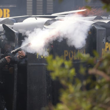 A police officer in protective gear fires tear gas