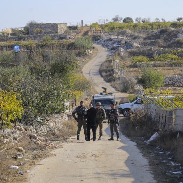 Palestinians stand behind a barrier as Israeli forces block farmers from accessing their lands in Halhul town near Hebron, in the occupied West Bank, on November 20, 2025.