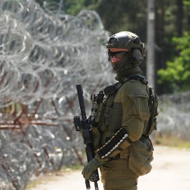A Polish border guard stands near a barbed wire fence at the Polish-Belarusian border in Polowce, Poland, July 21, 2025. © 2025 AP Photo/Czarek Sokolowski