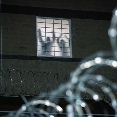 Detainees stand by a window inside the federal immigration center at Delaney Hall