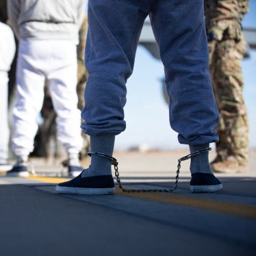 People in ankle chains board a plane