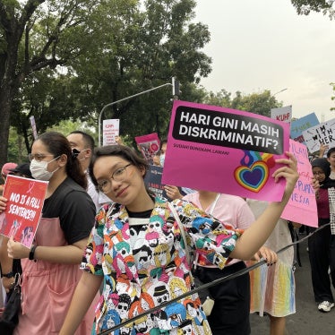 A young protester raises a poster, “Today still discriminatory?” with the love rainbow sign during the Women’s March rally in March 2023 in Jakarta, Indonesia. 