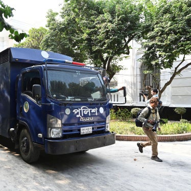 Journalists swarm a blue prison van