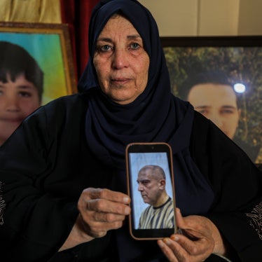 Samira Hahami stands in front of photos of her son, Hamza Ali al-Khatib, who at the age of 13 in May 2011, died in security forces custody. His body bore apparent signs of torture.