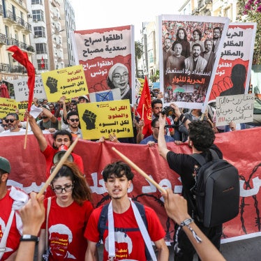 Tunisians hold up placards during a march organized by the Campaign Against the Criminalization of Civil Work to protest racism in Tunis, April 11, 2026