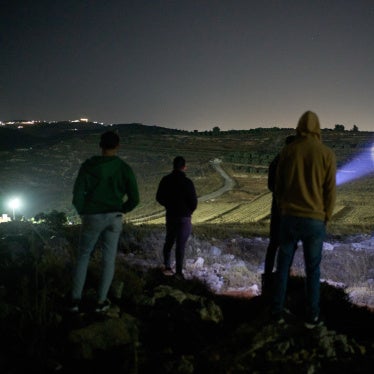 A Palestinian uses a flashlight on a nearby hill while taking part in a night watch with other volunteers to deter settler attacks on the West Bank village of Sinjil, July 16, 2026.