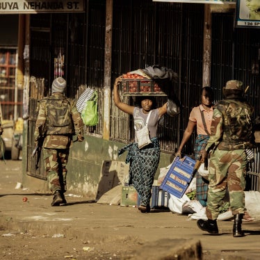 A vendor seeks cover as soldiers disperse demonstrators in Harare, Zimbabwe, after protests erupted over alleged fraud in the country's election on August 1, 2018.