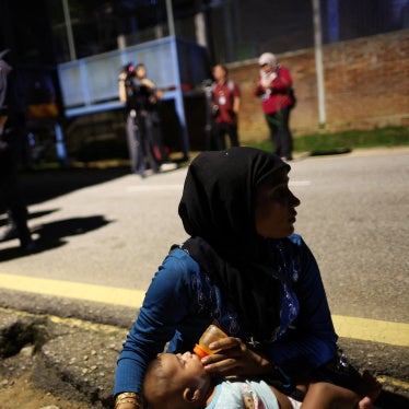 A Rohingya refugee feeds a child in front of the office of the UN refugee agency in Kuala Lumpur, Malaysia, July 27, 2026. 