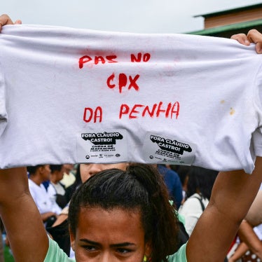 A woman holds up a shirt with a message in Portuguese on it during a protest