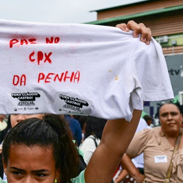 A woman holds up a shirt with a message in Portuguese on it during a protest