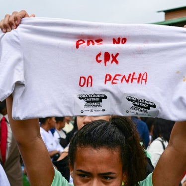 A woman holds up a shirt with a message in Portuguese on it during a protest