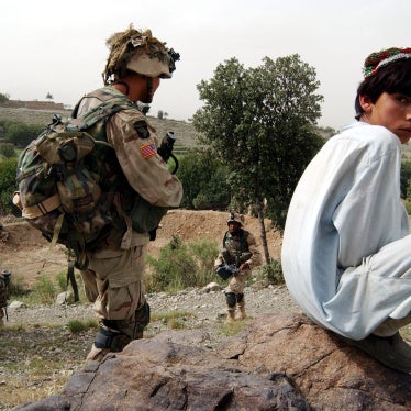 An Afghan boy watches as US Army 101st Airborne soldiers move in during a mission in southeastern Afghanistan, July 23, 2002. 