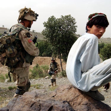 An Afghan boy watches as US Army 101st Airborne soldiers move in during a mission in southeastern Afghanistan, July 23, 2002. 