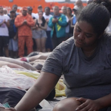 A woman sits among a crowd of people looking down