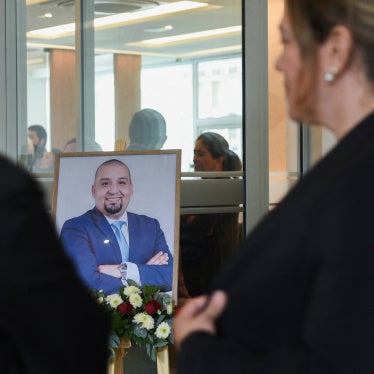 People stand near a framed photo of Guatemalan lawyer and anti-corruption figure Juan Francisco Solorzano Foppa, who died after being shot by unknown assailants on Saturday while visiting a sports center, during his wake at a funeral home in Guatemala City, Guatemala, October 19, 2026.