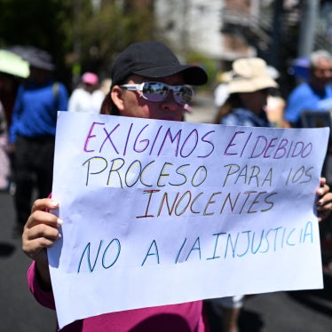 A woman holds a sign reading "We demand due process for the innocent. No to injustice" during a protest 