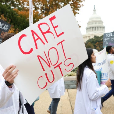 Protesters hold a placard that reads "Care Not Cuts"