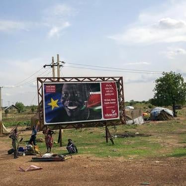 Civilians gather in front of a sign celebrating the second anniversary of South Sudan's independence as they prepare to flee from renewed attacks.