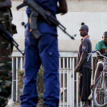 Residents look on as police and soldiers guard a voting station in the Burundian capital, Bujumbura, during presidential elections on July 21, 2015.