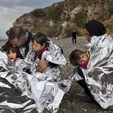A family sits on the shore of the Greek island of Lesbos wrapped in thermal blankets after journeying from Turkey aboard a rubber boat. October 11, 2015. © 2015 Zalmaï for Human Rights Watch