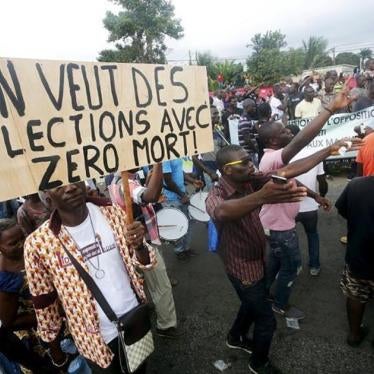 Members of the opposition National Coalition for Change hold a sign reading "We want election with zero dead" as they chant slogans during a protest march in Abidjan, Côte d’Ivoire on September 28, 2015