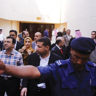 A police officer holds back journalists as doctors and nurses emerge during a break in their civilian criminal court trial on November 28, 2011 in Manama, Bahrain.