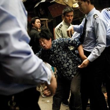 A woman fights with chengguan police as they dismantle part of her small restaurant and confiscate equipment that she stored on the sidewalk outside of her shop in the Fuzi Miao tourist market in central Nanjing, Jiangsu, China. 