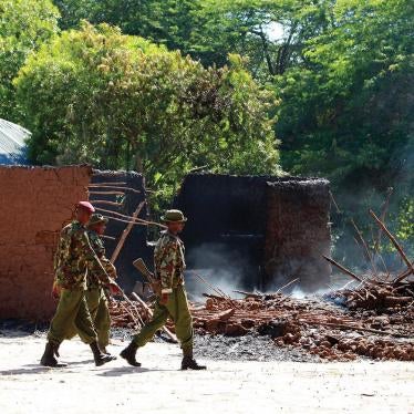 Kenyan police officers walk past the remains of burnt houses after an attack in Kibusu village in Tana River County of the Kenyan Coast on January 10, 2013. Inter-ethnic clashes in 2012 and early 2013 claimed about 180 lives. 