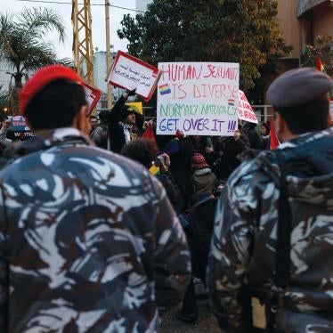 In this Sunday, Feb. 22, 2009 picture, Lebanese police stand guard as protesters carry banners during a sit-in for gays and lesbians in Beirut. 