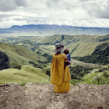 A woman holding a child looks down the valley from Kassam Pass.