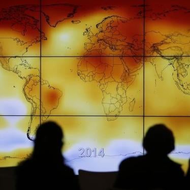 Participants are seen in silhouette as they look at a screen showing a world map with climate anomalies during the World Climate Change Conference 2015 (COP21).