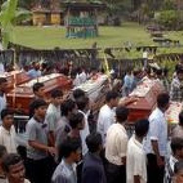 People walk past the coffins of five killed Sri Lankan Tamil students during a funeral procession in Trincomalee, eastern Sri Lanka, on January 5, 2006.