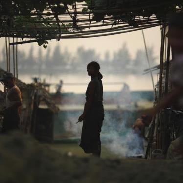 A woman is silhouetted as she stands outside her hut near the bank of Yangon River March 18, 2012.