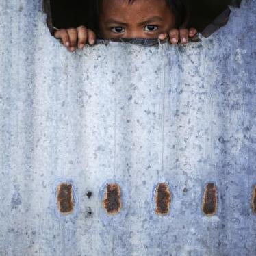 A child peers from inside a makeshift house with tin walls in Tacloban, Philippines, January 15, 2015.