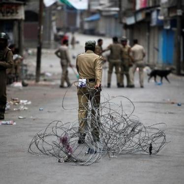 An Indian policeman pulls concertina wire to lay a barricade on a road during a curfew in Srinagar on July 12, 2016. 