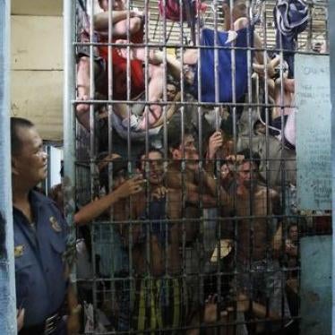 A policeman looks on at prisoners crowded into a detention cell in Manila, Philippines on May 13, 2011. 