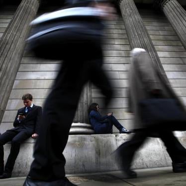 A man and woman use their mobile phones as commuters walk past the columns of the Bank of England in the City of London, July 3, 2012. 